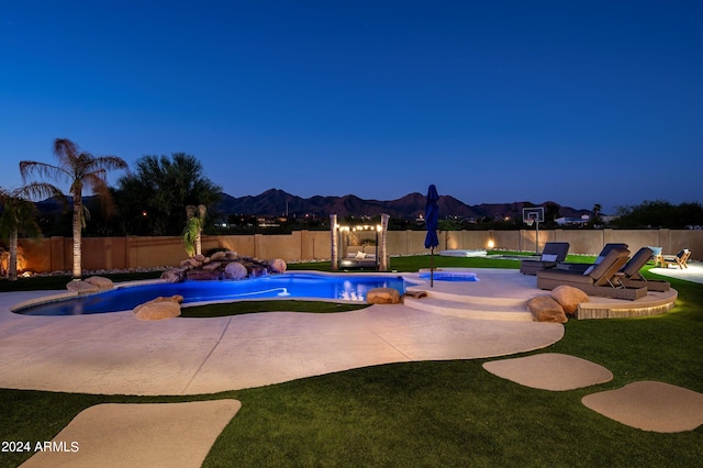 pool at night featuring a lawn and a patio area