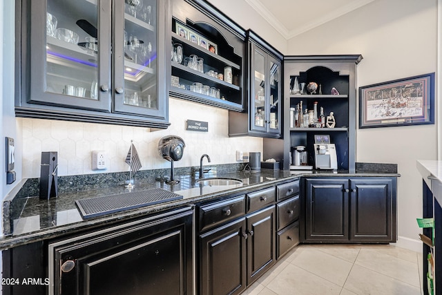 kitchen featuring crown molding, dark stone countertops, sink, and light tile patterned floors