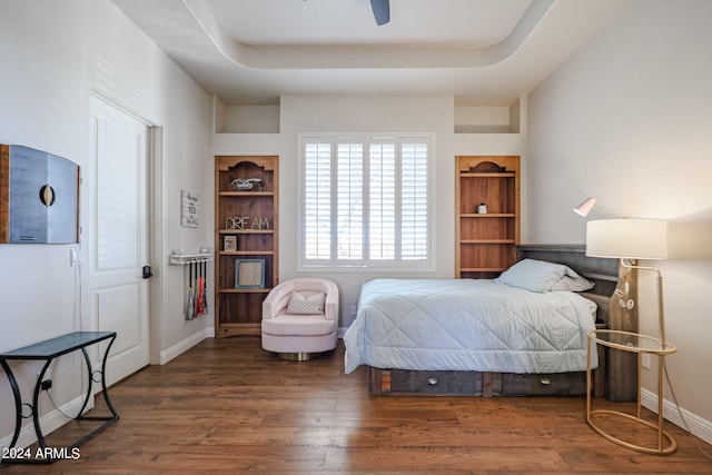 bedroom with ceiling fan, a raised ceiling, and dark wood-type flooring