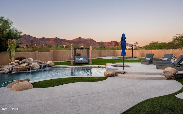 pool at dusk featuring pool water feature, a patio, and a mountain view