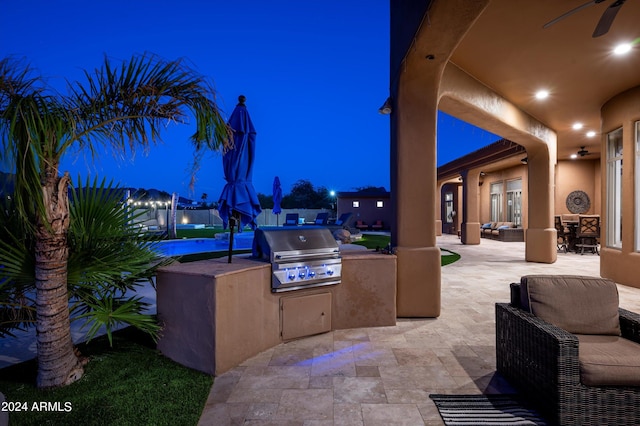 patio at night featuring exterior kitchen and grilling area