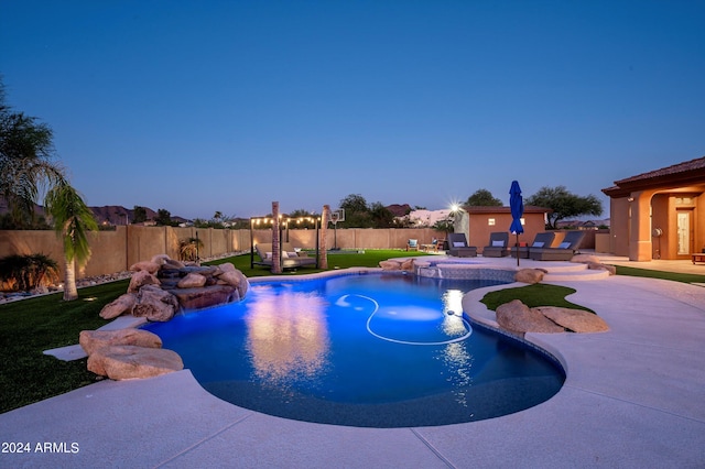 pool at dusk with a yard, pool water feature, and a patio area