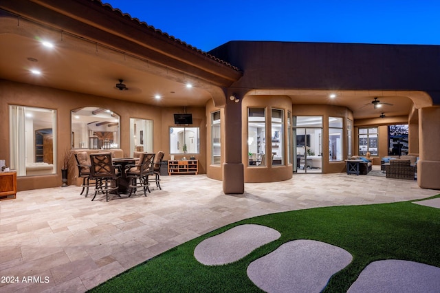 patio at night featuring ceiling fan and an outdoor hangout area