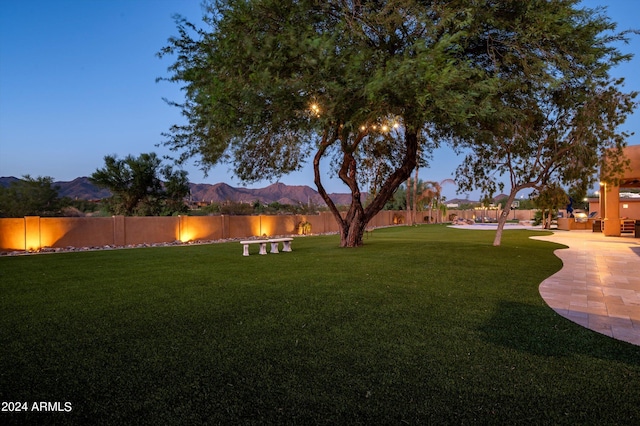 yard at dusk with a patio and a mountain view