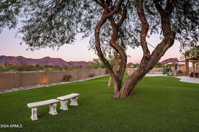 yard at dusk featuring a mountain view and a patio area