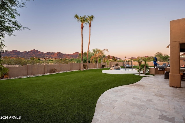 yard at dusk featuring a patio and a mountain view