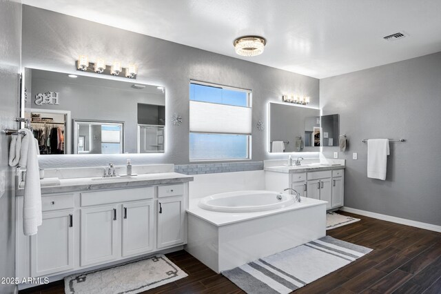 21328 E Misty Ln, Queen Creek, AZ 85142 - bathroom featuring two vanities, a bath, visible vents, wood finished floors, and a sink