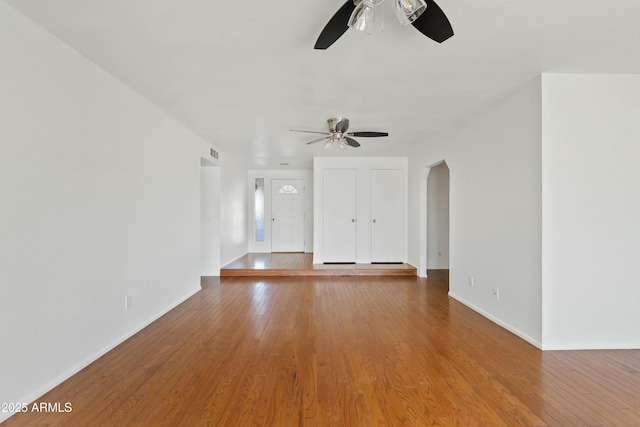unfurnished living room with light wood-style flooring, baseboards, and a ceiling fan