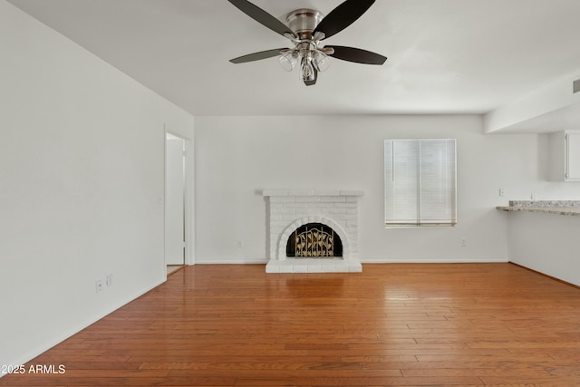 unfurnished living room featuring a fireplace, a ceiling fan, baseboards, and hardwood / wood-style flooring