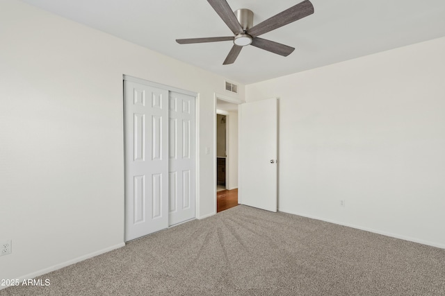 unfurnished bedroom featuring a closet, a ceiling fan, visible vents, carpet floors, and baseboards