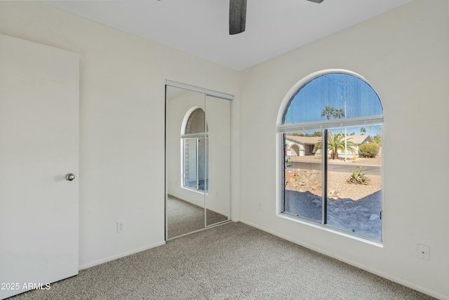 unfurnished bedroom featuring ceiling fan, a closet, baseboards, and carpet floors