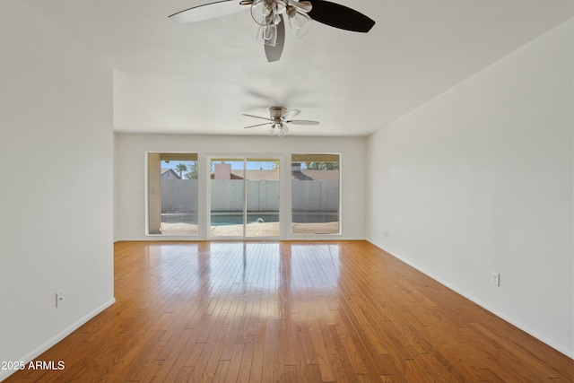empty room featuring hardwood / wood-style floors, baseboards, and a ceiling fan