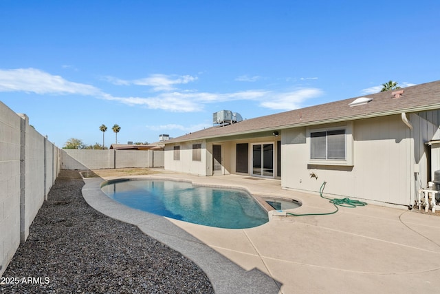 view of pool with a patio, a fenced backyard, a pool with connected hot tub, and central AC unit