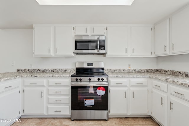 kitchen with white cabinets, a skylight, and appliances with stainless steel finishes