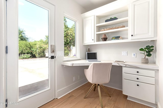 home office with light wood-type flooring, built in desk, and plenty of natural light