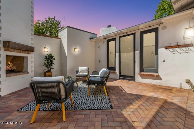 patio terrace at dusk featuring an outdoor fireplace