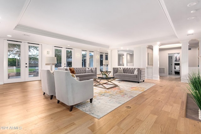 living room featuring ornate columns, ornamental molding, french doors, light hardwood / wood-style floors, and a tray ceiling