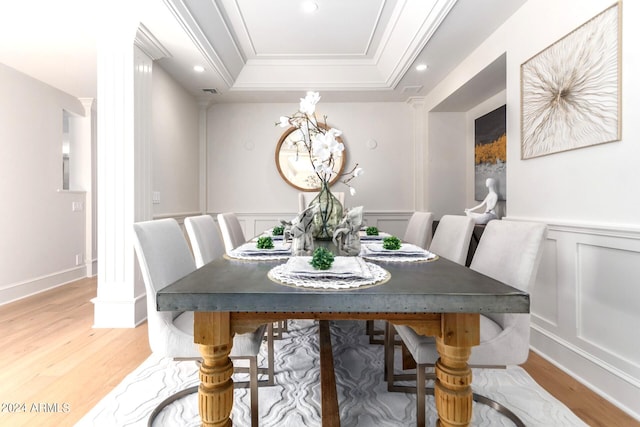 dining space featuring a raised ceiling, hardwood / wood-style flooring, and crown molding