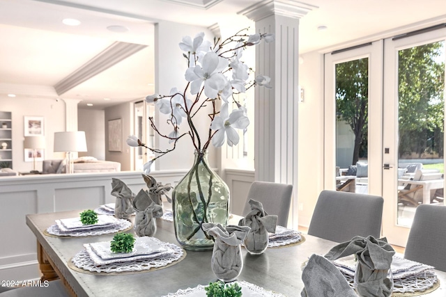 dining space featuring a raised ceiling, french doors, crown molding, and ornate columns