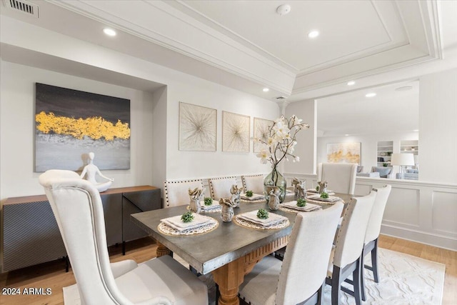 dining room featuring a raised ceiling and light hardwood / wood-style flooring