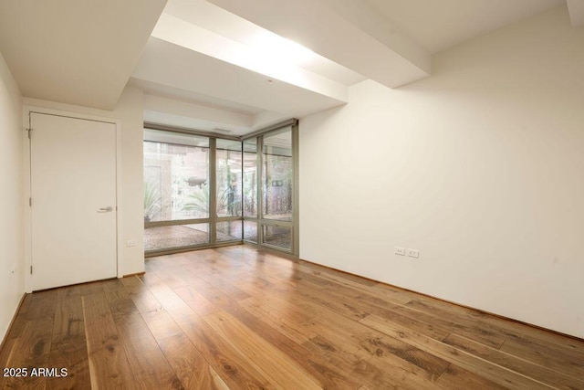 unfurnished room with a wall of windows and hardwood / wood-style floors