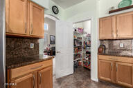 818 E Hiddenview Dr, Phoenix, AZ 85048 - kitchen with decorative backsplash, arched walkways, dark countertops, and brown cabinets