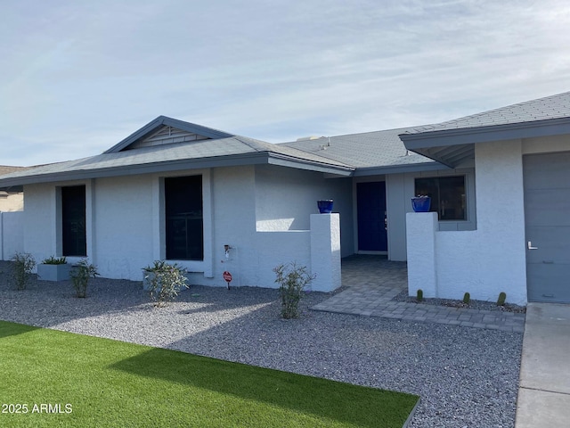 exterior space featuring roof with shingles and stucco siding