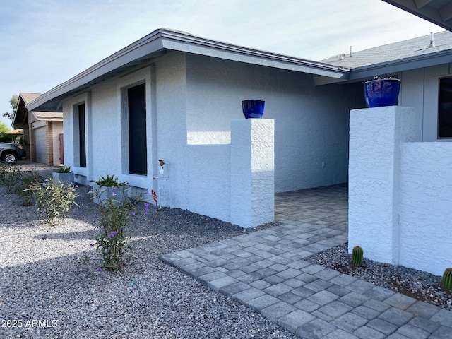 view of property exterior with a garage, roof with shingles, and stucco siding