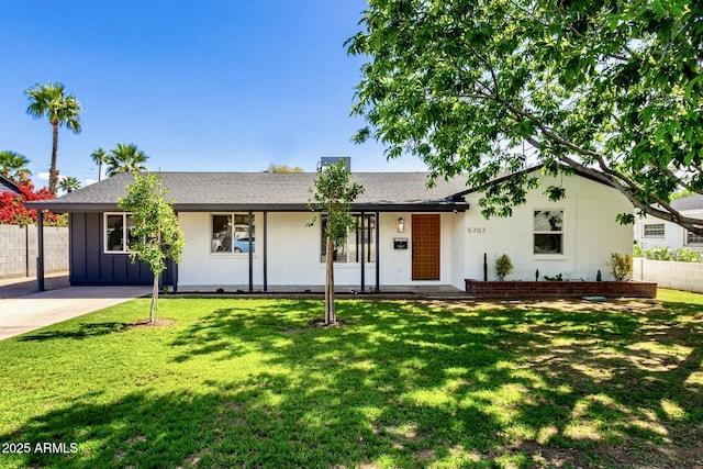 ranch-style home featuring a front yard, board and batten siding, and fence
