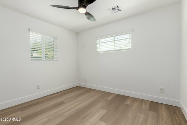 empty room featuring light wood-type flooring, ceiling fan, visible vents, and a wealth of natural light