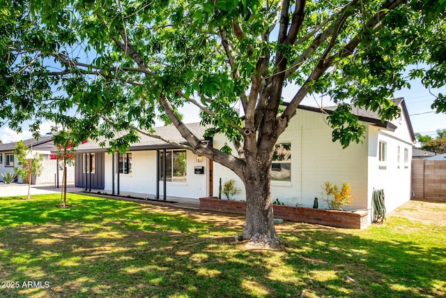 view of front of home featuring a shingled roof, a front yard, fence, and brick siding