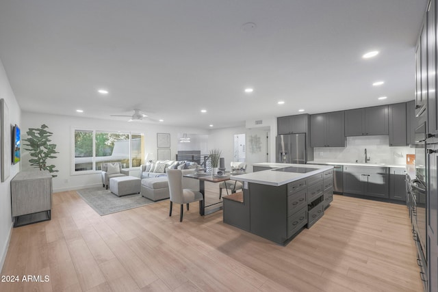 kitchen featuring stainless steel appliances, a kitchen island, light wood-type flooring, sink, and ceiling fan