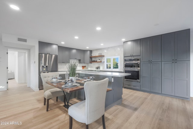 kitchen featuring light wood-type flooring, appliances with stainless steel finishes, gray cabinets, and a kitchen island