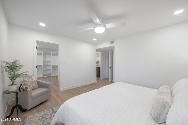 bedroom with a closet, a walk in closet, ceiling fan, and light hardwood / wood-style flooring