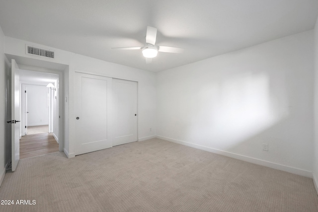 unfurnished bedroom with ceiling fan, light carpet, and a closet