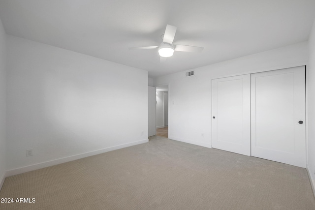 unfurnished bedroom featuring ceiling fan, light carpet, and a closet