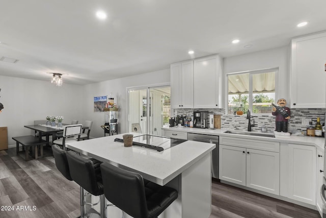 kitchen with dark hardwood / wood-style flooring, white cabinets, sink, dishwasher, and a center island