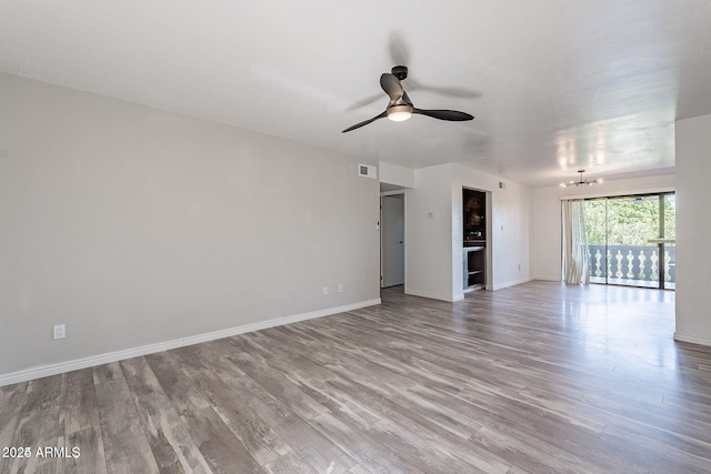 unfurnished living room with wood finished floors, a chandelier, ceiling fan, and baseboards