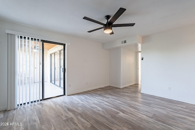 spare room with wood finished floors, ceiling fan, and baseboards