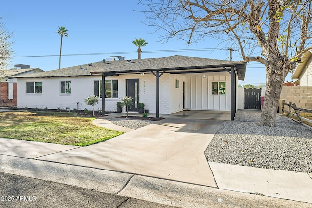 ranch-style home featuring concrete driveway, board and batten siding, fence, and roof with shingles