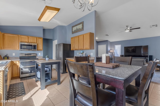 dining area featuring ceiling fan with notable chandelier, sink, light tile patterned flooring, and vaulted ceiling