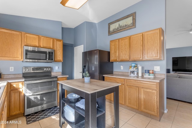 kitchen featuring ceiling fan, light tile patterned floors, appliances with stainless steel finishes, and a towering ceiling