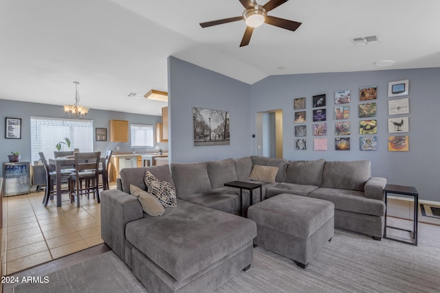 tiled living room featuring ceiling fan with notable chandelier and vaulted ceiling