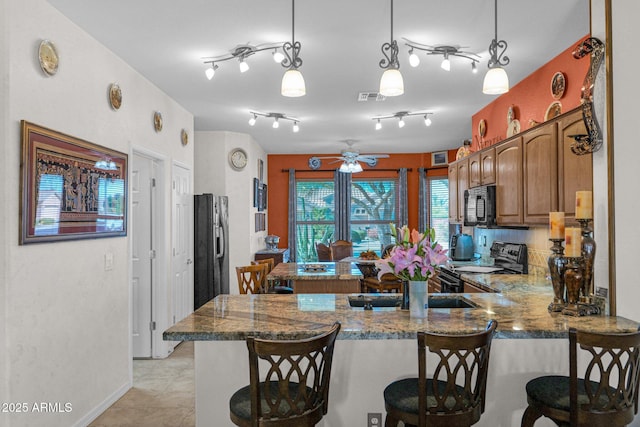 kitchen featuring a breakfast bar area, pendant lighting, kitchen peninsula, and black appliances