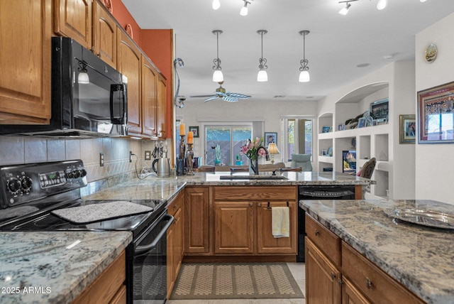 kitchen featuring pendant lighting, black appliances, kitchen peninsula, sink, and light stone counters