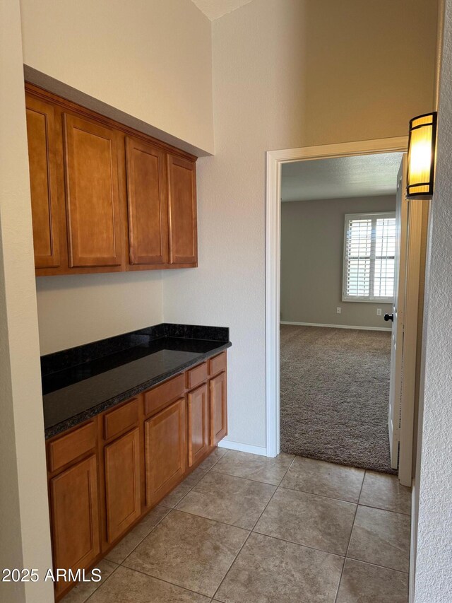2077 N Lake Shore Dr, Casa Grande, AZ 85122 - kitchen featuring open floor plan, light colored carpet, light tile patterned floors, baseboards, and brown cabinets