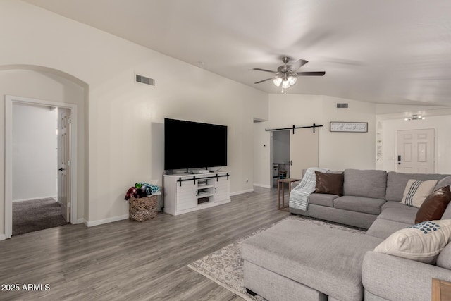 living room featuring hardwood / wood-style flooring, a barn door, and ceiling fan