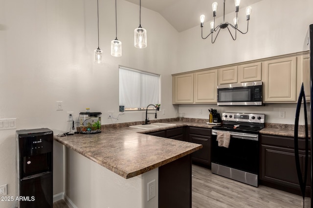 kitchen with pendant lighting, high vaulted ceiling, sink, stainless steel appliances, and cream cabinetry