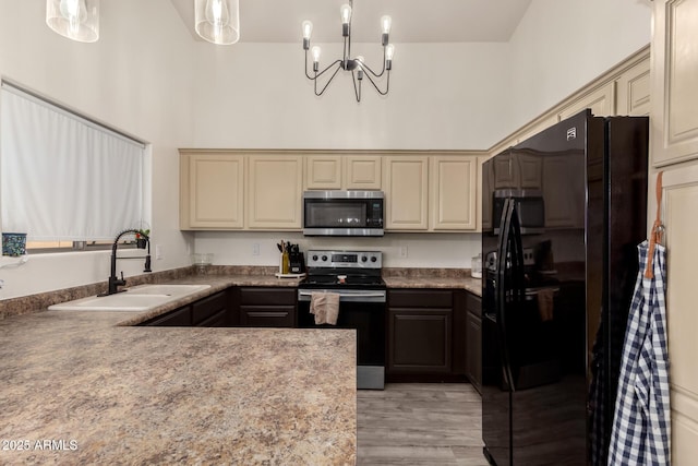 kitchen featuring appliances with stainless steel finishes, a towering ceiling, pendant lighting, sink, and cream cabinets