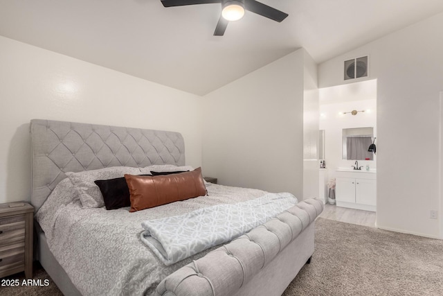 bedroom with lofted ceiling, ensuite bathroom, sink, light colored carpet, and ceiling fan